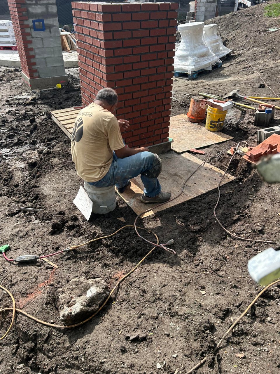 Mason connecting plumbing and stonework during fountain installation project
