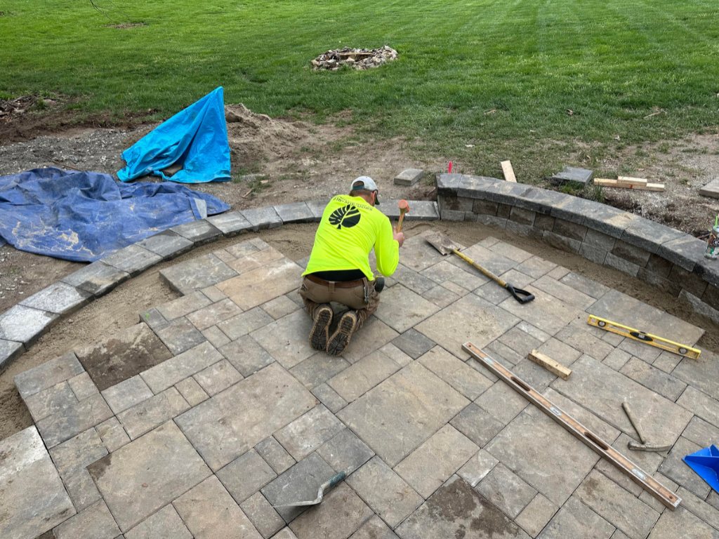 Worker installing stone pavers for custom backyard patio in Johnson County