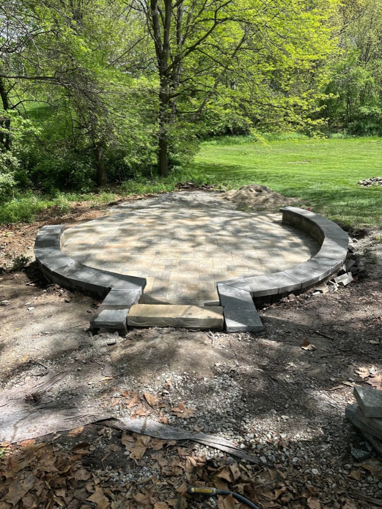 Circular patio installation with stone border edging under construction